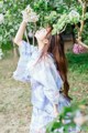 A woman in a blue kimono standing in front of a tree.