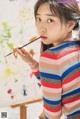 A young girl is painting on a canvas with a brush.