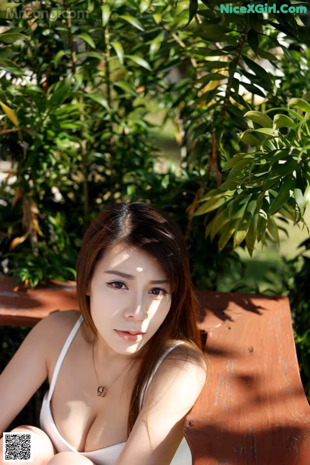 A woman in a white bikini sitting on a bench.