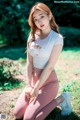 A woman in a white top and pink leggings sitting on the ground.