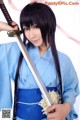 A woman in a blue kimono holding a sword.