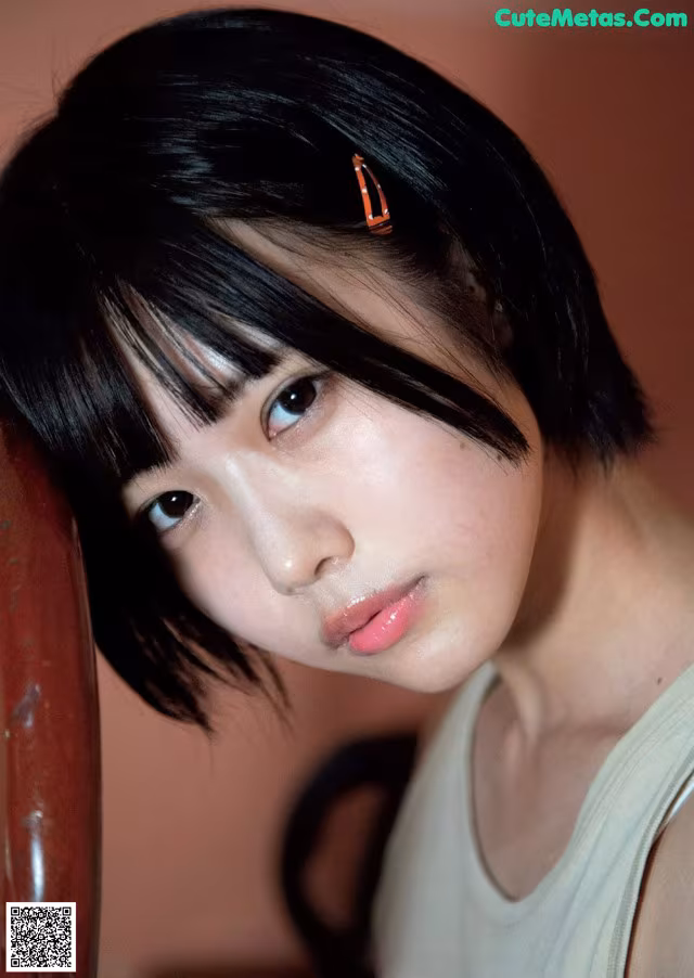 A woman with black hair and a white tank top.