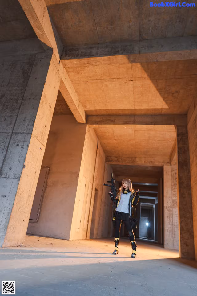 A woman holding a gun standing in an empty building.