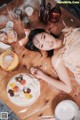 A woman laying on a wooden table next to a plate of food.