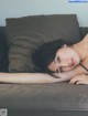 A woman laying on top of a couch next to a pillow.