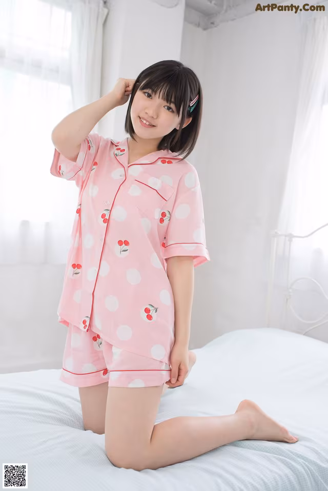 a woman sitting on top of a bed wearing a pink pajamas