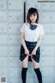 A woman in a school uniform posing in front of lockers.