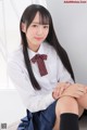 A young woman in a school uniform sitting on the floor.