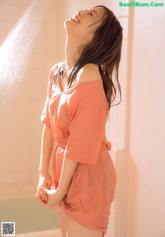 A woman standing in a bathroom next to a shower.