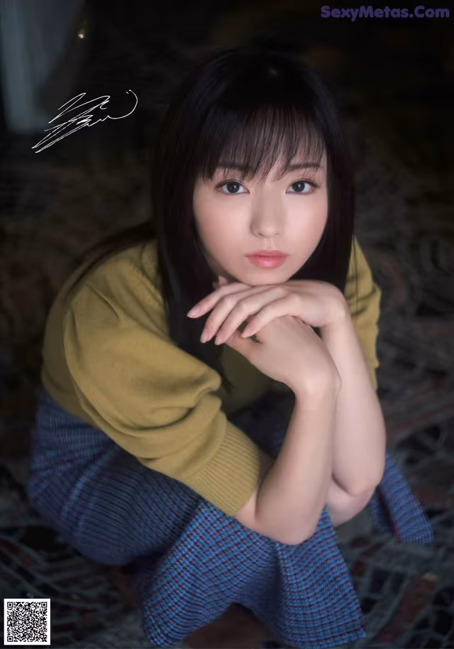 A woman sitting on the ground with her hand on her chin.
