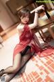A woman in a red lingerie sitting on the floor.
