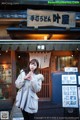 A woman standing in front of a building holding a cell phone.