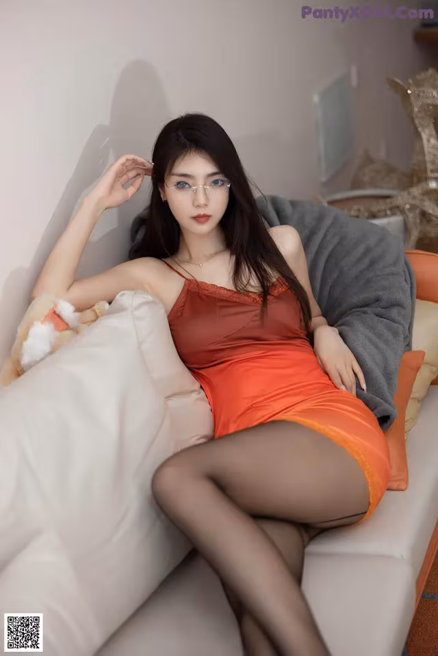 A woman in a red dress sitting on a white couch.