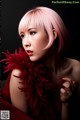 A woman with pink hair and a red feather boa.